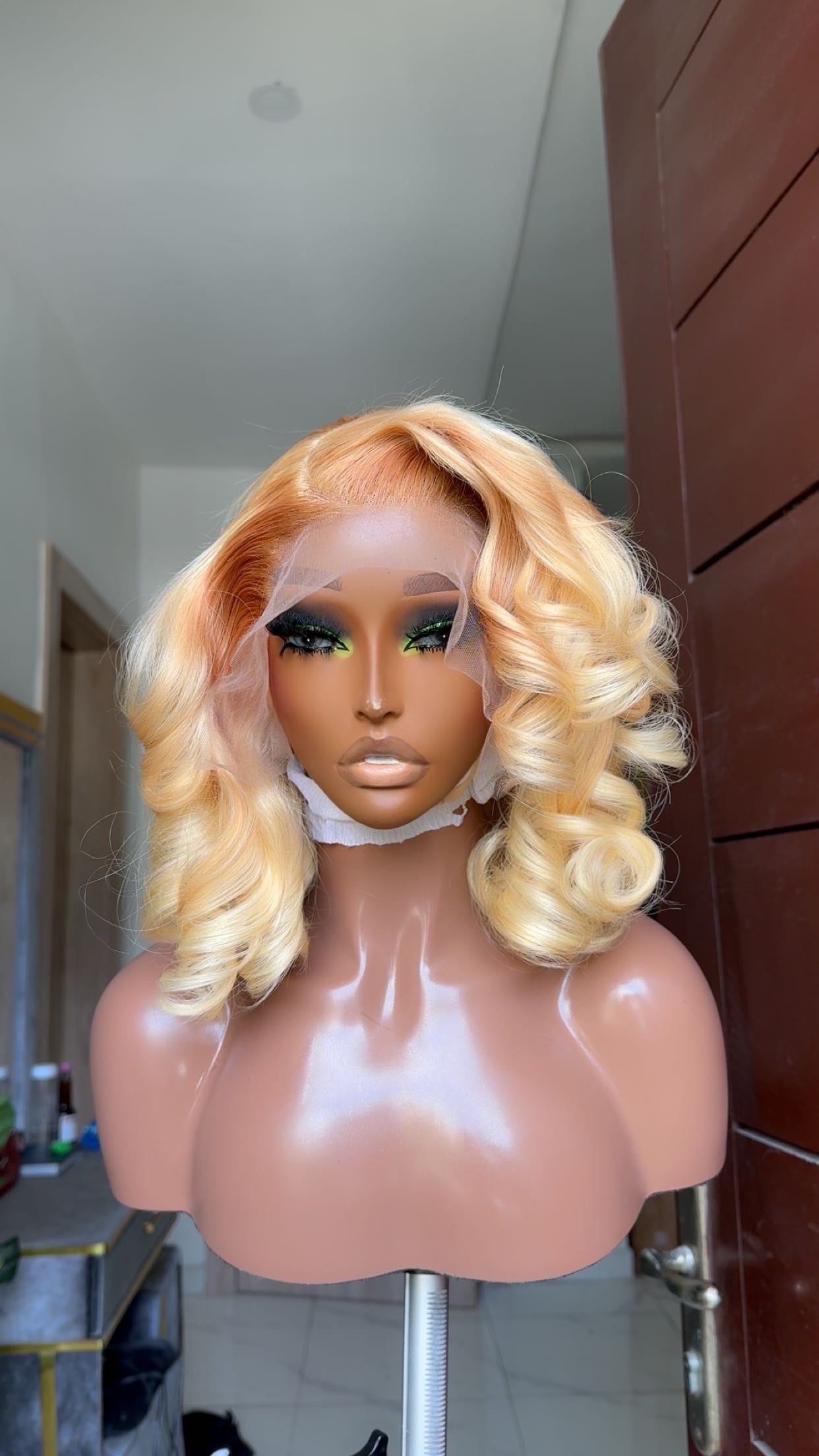 Blonde wig on a mannequin head against a neutral background